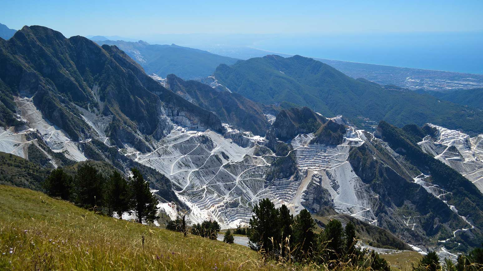 Radreise Toskana: Diesen Traumblick werden Sie erleben. Blick auf die Marmorbrüche von Carrara und die Ligurische Küste. Ganz links am Meer liegt unser Hotel Versilia Palace